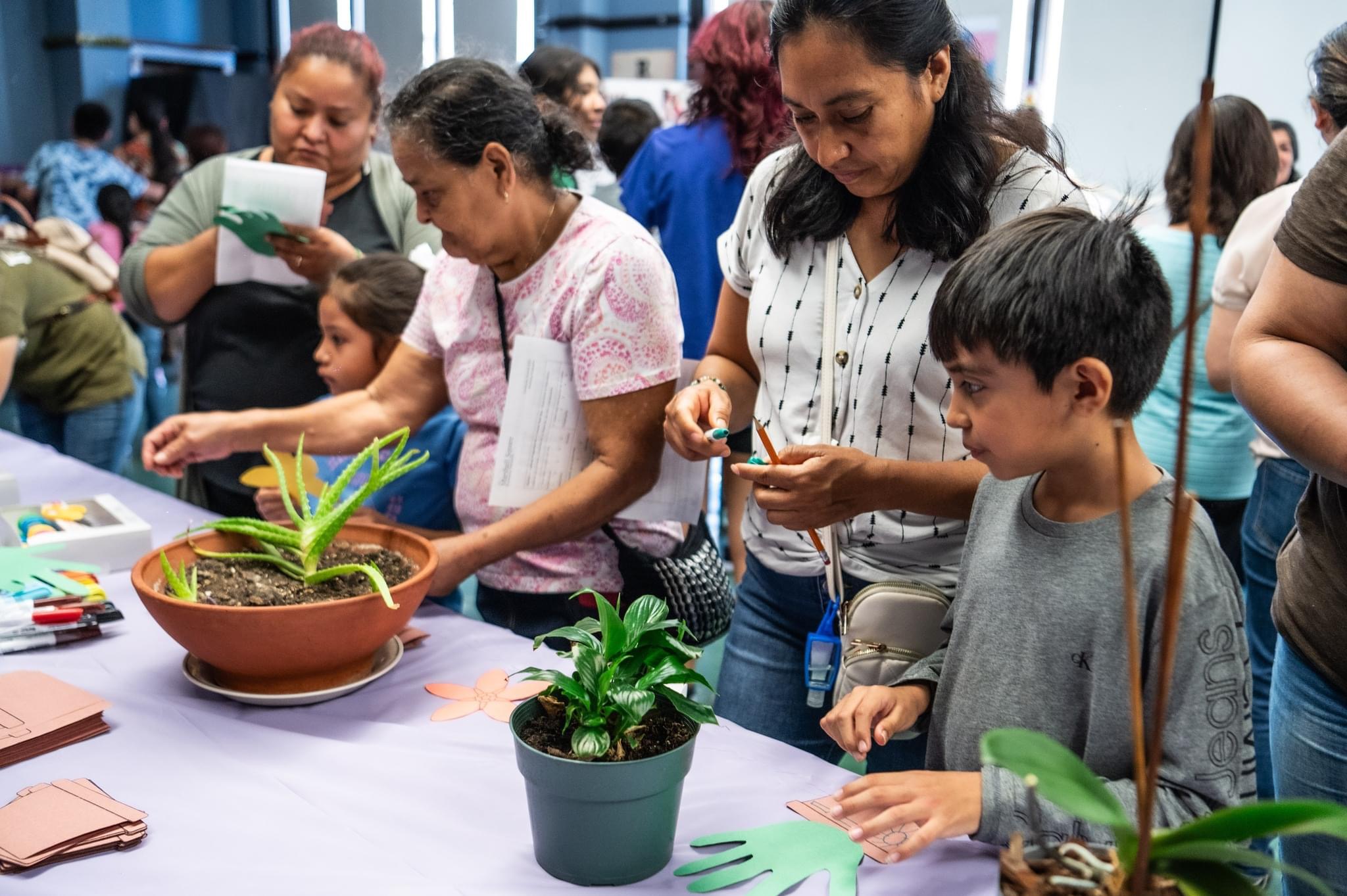 children and adults work with potted plants together
